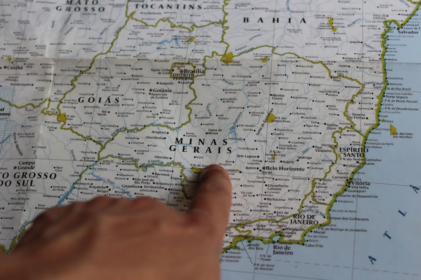 Dedo apontando uma cidade num mapa do Brasil